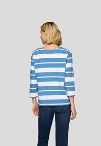 Blau-weiß gestreiftes Oberteil mit 3/4-Ärmeln, weicher Stoff mit lockerer Passform. Rückansicht zeigt runden Ausschnitt und Nähdetails. Getragen mit dunklen Jeans.