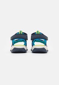 Marineblå sandaler med justerbare stropper, gule detaljer og en teksturert gummisåle. Åpen design for pusteevne og komfort.