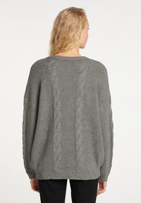Grauer gestrickter Pullover mit einem gerippten Textur und Kabelstrickdetails an den Seiten sowie einem lockeren Schnitt. Rundhalsausschnitt.