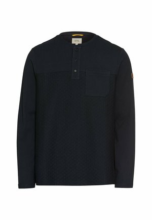 Chemise à manches longues bleu foncé avec une partie supérieure texturée, un col henley à trois boutons et une poche sur la poitrine gauche. Tissu doux.
