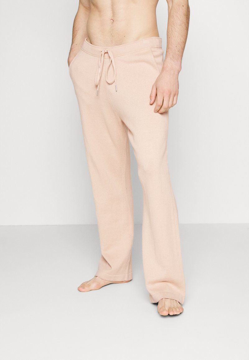 Calças de lounge de tecido suave, cor rosa claro, com cintura ajustável, corte amplo e costuras mínimas, proporcionando um ajuste relaxado.
