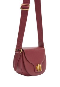 Malá texturovaná křížová kabelka v burgunďské barvě z kůže s klopou, zlatě tónovaným zapínáním a širokým nastavitelným textilním popruhem s embosovaným nápisem.