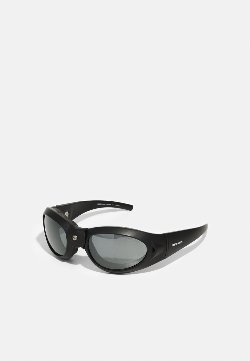 Gafas de sol negras con un diseño envolvente, lentes grises, montura texturizada y pequeños acentos metálicos en la parte frontal. Construcción ligera.