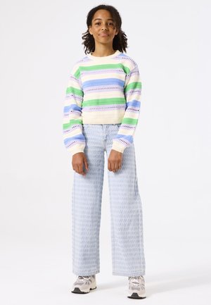 Pull rayé multicolore en vert pastel, violet et bleu avec un ourlet crème ; large pantalon texturé bleu clair ; chaussures de sport grises.