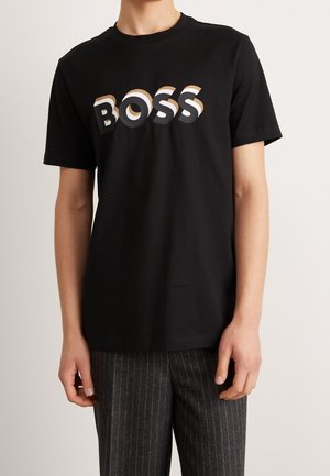 Black cotton t-shirt featuring raised "BOSS" logo in gradient colors. Classic crew neck design with short sleeves, soft texture.