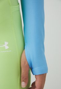 Helesoovidega kerge sinine sportlik topp, millele on lisatud sobiv roheline aluskiht. Omab siledat tekstuuri ja tihedaid mansette.
