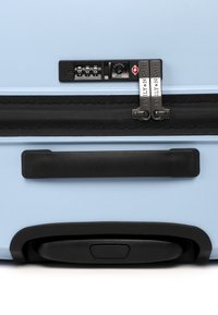 Tvrdý kufr ve světlé modré barvě s texturovaným povrchem, černým zipem, integrovaným kombinovaným zámkem a dvojitými kovovými táhly zipu.