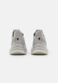 Szare sneakersy z siateczkową górną częścią, z połyskującą, wzorzystą nakładką i masywną, teksturowaną białą podeszwą. Tył buta zawiera pętelkę do łatwego zakładania.