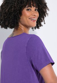 Lilla kortærmet t-shirt med rund halsudskæring, lavet af blødt stof, med en let tekstureret overflade og en afslappet pasform.
