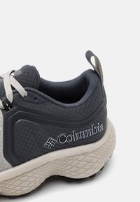 Adidași gri cu un superior din material texturat, guler căptușit și o talpă intermediară de culoare deschisă cu detalii ale logo-ului și o talpă din cauciuc cu model.