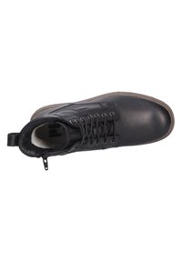 Botín de cuero negro hasta el tobillo con punta redondeada, diseño con cordones y cremallera lateral. Presenta adornos texturizados y una suela de goma en color marrón claro.