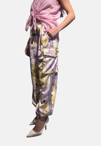 Pantaloni cargo floreali in colori pastello con una texture simile alla satin, polsini elasticizzati e molteplici tasche, abbinati a tacchi chiari.