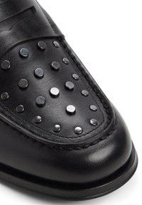 Zwarte leren schoen met ronde zilveren studs, een gestikt randje en een gladde textuur. Heeft een iets afgeronde neus en een minimalistisch ontwerp.