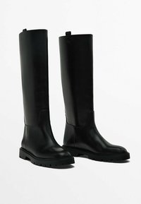 Bottes noires en cuir jusqu'au genou avec une texture lisse, un bout arrondi et une semelle en caoutchouc épaisse. Dotées d'une languette en haut pour un enfilage facile.