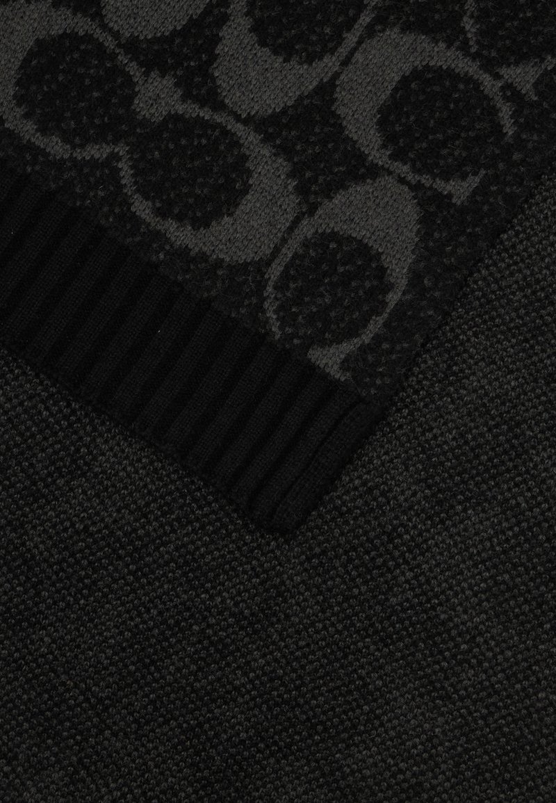 Schwarzer Stoff mit einem strukturierten Muster aus Kreisen. Der untere Rand hat eine gerippte Oberflächenstruktur, die zur insgesamt dunklen Erscheinung beiträgt.