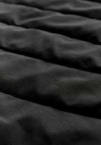 Schwarzer gepolsterter Stoff mit einer glatten Textur, der genähte vertikale Kanäle aufweist, die ein gestepptes Muster bilden. Einheitliche Farbe im gesamten Stoff.