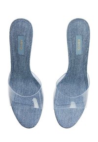 Mule in denim con fasce trasparenti, tessuto testurizzato e suole imbottite. La soletta include un'etichetta blu con scritte dorate.
