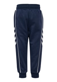 Jogging navy en tissu lisse, avec des rayures blanches sur les côtés et une taille élastique ainsi que des poignets élastiques pour un ajustement confortable.