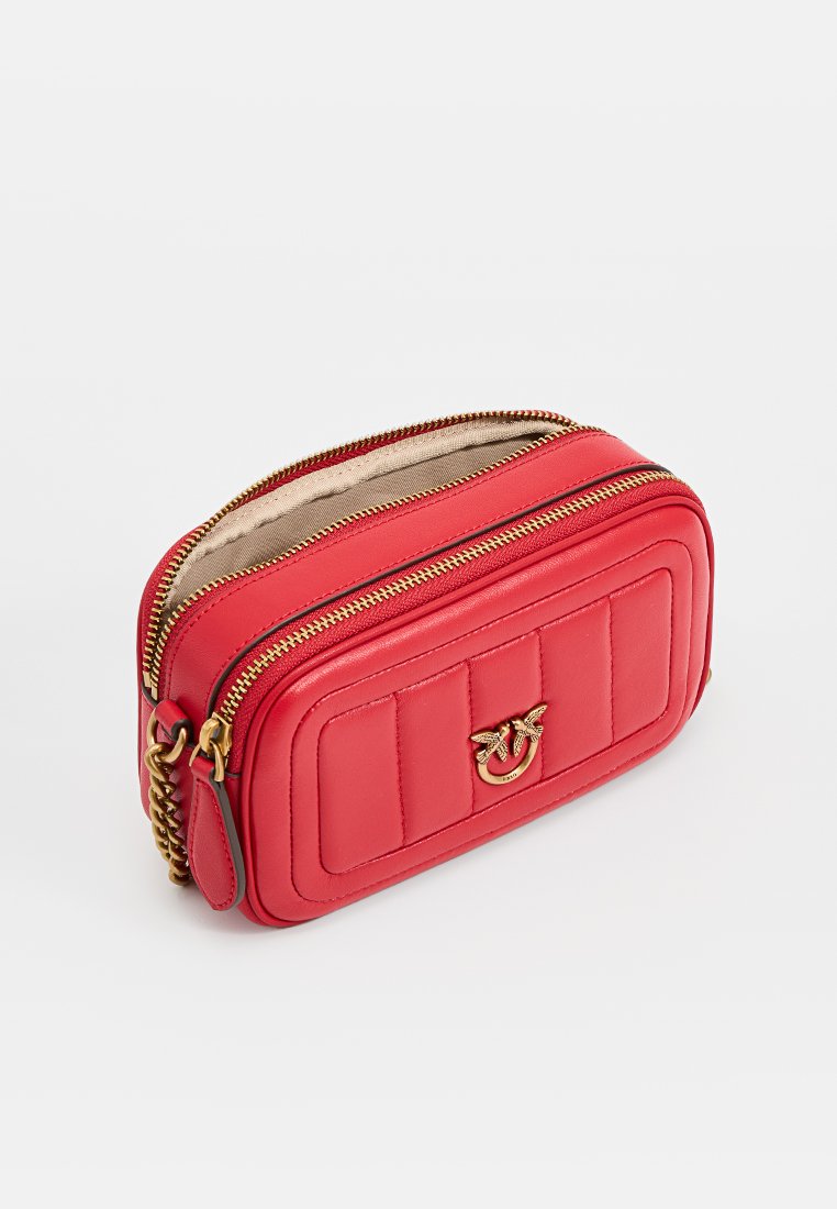 Pochette en cuir rouge avec un design matelassé, quincaillerie dorée et double fermeture éclair. Présente un accent logo sur le devant et un intérieur doublé en tissu.