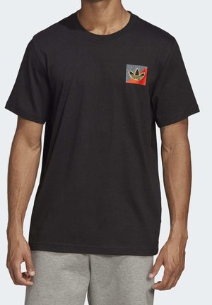 T-shirt nera in cotone con una piccola tasca multicolore stampata con strisce e un logo. Maniche corte e scollatura rotonda.