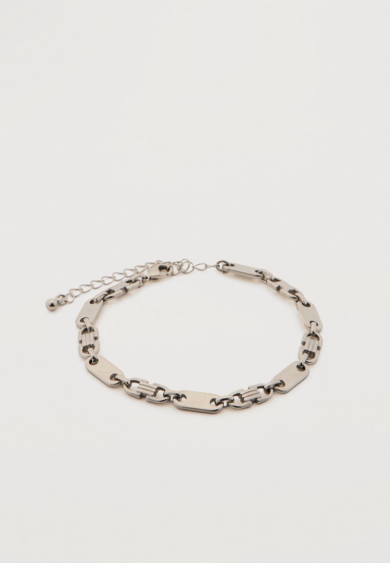 Ασημί μεταλλικό βραχιόλι αλυσίδας με εναλλάξ ορθογώνιους και οβάλ κρίκους, ρυθμιζόμενο κούμπωμα με μικρό στρογγυλό μπρελόκ σε λευκό φόντο.
