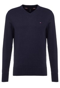 Granatowy sweter z dekoltem w serek wykonany z miękkiego materiału, z długimi rękawami i małym logo na lewej piersi. Prosty, klasyczny design.