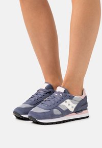 Marineblå semsket lær og mesh sneakers med lyserøde accenter, hvidt logo og sort gummisål. Lav profil med snørelukning og polstret krave.