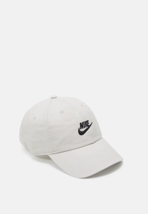 Weiße Nike-Baseballkappe mit schwarzem Logo, das vorne aufgestickt ist, vor einem einfarbigen weißen Hintergrund dargestellt.