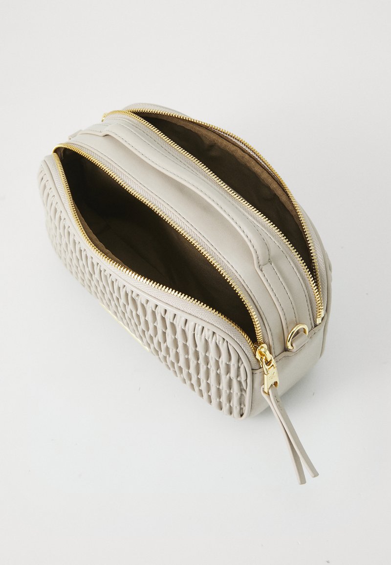 Szara skórzana saszetka o pikowanej fakturze, z dwiema zamykanymi na zamek komorami i złotymi akcentami. Gładka powierzchnia z kontrastowym wnętrzem.