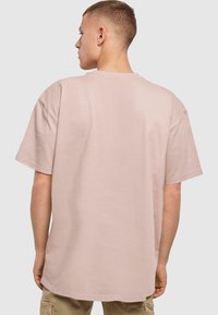 Lyserød bomulds T-shirt med en afslappet pasform, korte ærmer og rund halsudskæring. Blød tekstur med en glat overflade og ingen synlige mønstre eller detaljer.