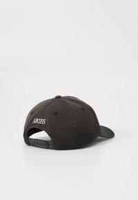 Svart caps med buet visir, laget av teksturert stoff. Har en justerbar plaststropp og brodert "ARIES"-logo på baksiden.