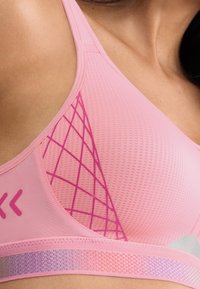 Rózsaszín sportmelltartó texturált anyaggal, gyémántmintás hálós részletekkel és rózsaszín árnyalatokból és ezüstből álló színátmenetes derékpánttal.