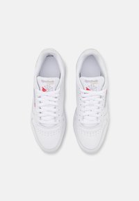 Vita Reebok-sneakers med en slät läder ovandel, rund tå, snörning, perforerade detaljer och logotypaccent i silver och rött.