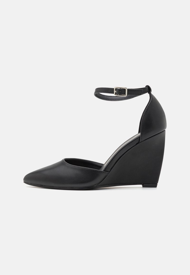 Chaussure à talon compensé noire avec un bout pointu, une bride à la cheville et une texture en cuir lisse. Dispose d'un talon compensé courbé pour une élévation stable.
