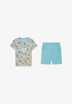 T-shirt blanc à manches courtes avec motifs du logo GUESS colorés et short bleu ciel avec poches avant et fermeture à bouton.