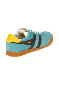 Zapatilla de ante azul con acento en el talón amarillo, rayas marrones, cordones blancos y suela de goma naranja. Cuenta con un interior acolchado.