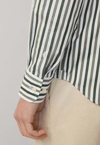 Camisa de manga larga a rayas con franjas verdes y blancas alternas, puños abotonados y un corte ajustado. Material de algodón suave.