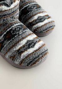 Vezelige, gestreepte sloffen in grijs, bruin en wit. Rondere neus, zachte textuur en een grijze suede-achtige bodem.