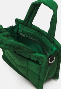 Sac à main matelassé vert avec anses rembourrées, un compartiment principal ouvert et une poche intérieure zippée visible à l’intérieur.