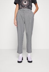 High-waisted, black and white houndstooth patterned trousers with side pockets, featuring a tailored fit and straight legs.