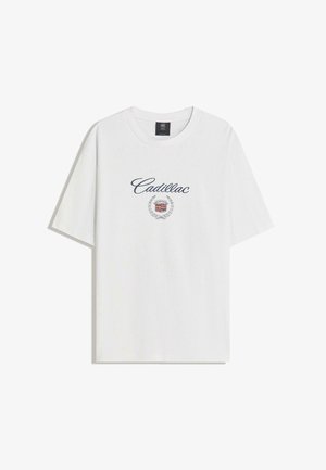 Bijela majica kratkih rukava s natpisom "Cadillac" i grbom loga smještenim ispod izreza.