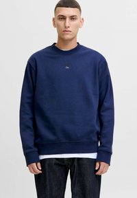 Navy blue sweatshirt in soft material, featuring a crew neckline, ribbed cuffs, and minimalistic embroidered text on the chest.
