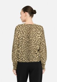 Suéter de estampado de leopardo en beige y marrón, con mangas largas y un dobladillo ligeramente corto. Confeccionado en un suave tejido de punto.