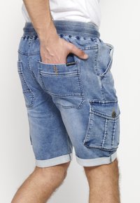 Denimshorts med en lys blå vask, som har flere lommer, opfoldede kanter og en elastisk talje for komfort.