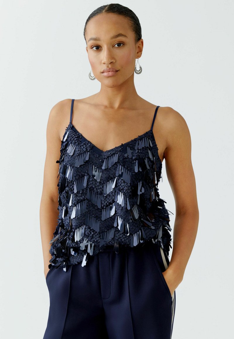 Navyblauer Tank-Top mit schimmernden Fransen-Details. Verstellbare Spaghettiträger und ein V-Ausschnitt-Design. Weiches, strukturiertes Material.