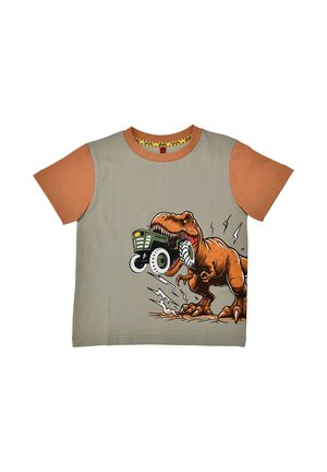 Maglietta con maniche arancioni e corpo beige con un T-Rex che morde un giocattolo verde a forma di trattore, circondato da linee di movimento in stile cartone animato.
