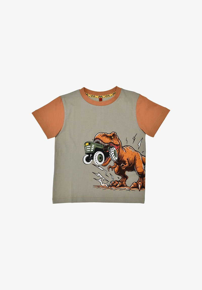 T-shirt avec manches orange et corps beige présentant un T-Rex mordant un tracteur jouet vert, entouré de lignes de mouvement dessinées.