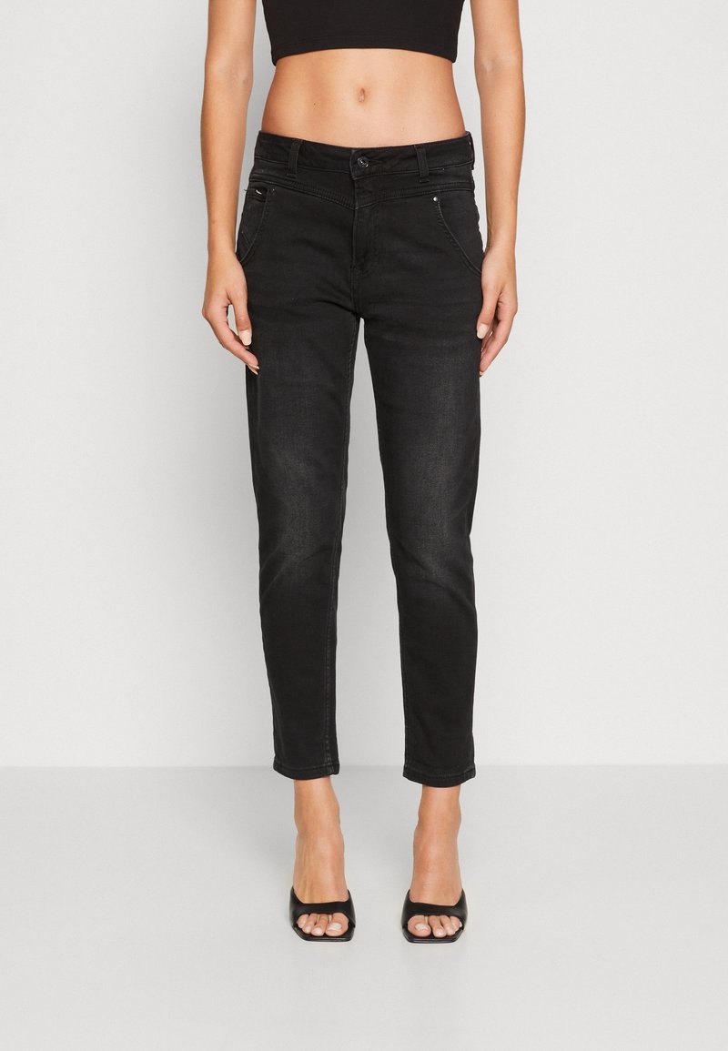 Svarta denimjeans med en åtsittande design, kort längd, fem fickor och lätt blekningsdetalj. I kombination med svarta öppna skor.