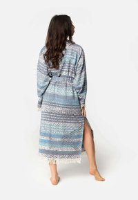 Dolga, ohlapna halja v modrih in sivozelenih odtenkih z mešanim vzorcem, s pripetim pasom in robom s fru fru, stranski razporek za udobje.