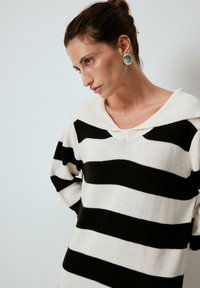 Randig tröja med breda svarta och off-white horisontella ränder, V-ringning och en oversized passform med en mjuk textur.